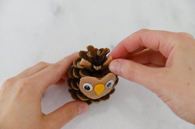 Gluing felt ears onto pine cone