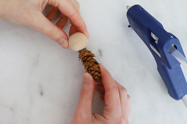 Gluing wood bead to pine cone