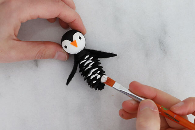 Painting pine cone penguin tummy