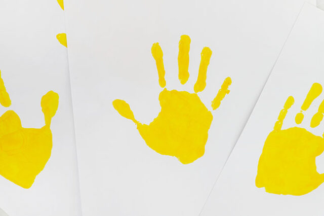 Yellow handprints on paper